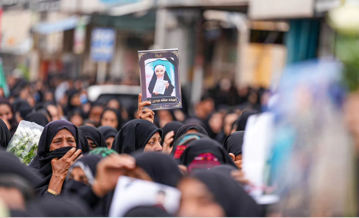 Thousands of mourners, including grieving families and local residents, gather to pay their respects to schoolgirls who were killed in a reported U.S. airstrike.