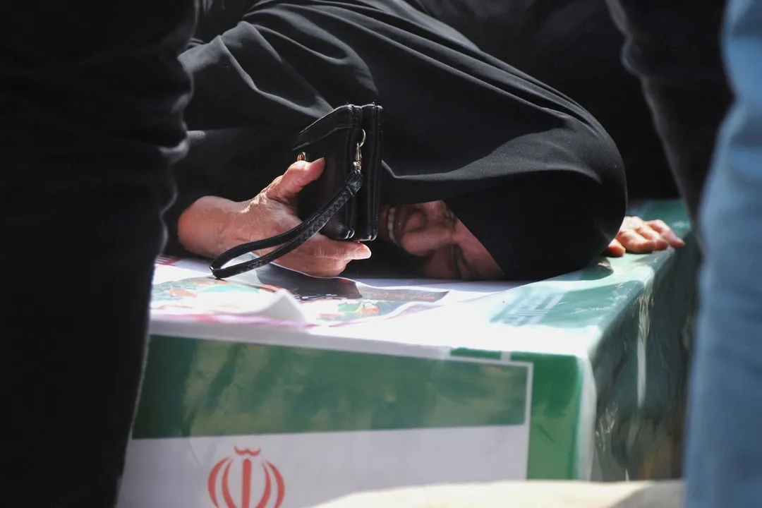 A grief-stricken mother weeps over the coffin of her daughter during a funeral procession.